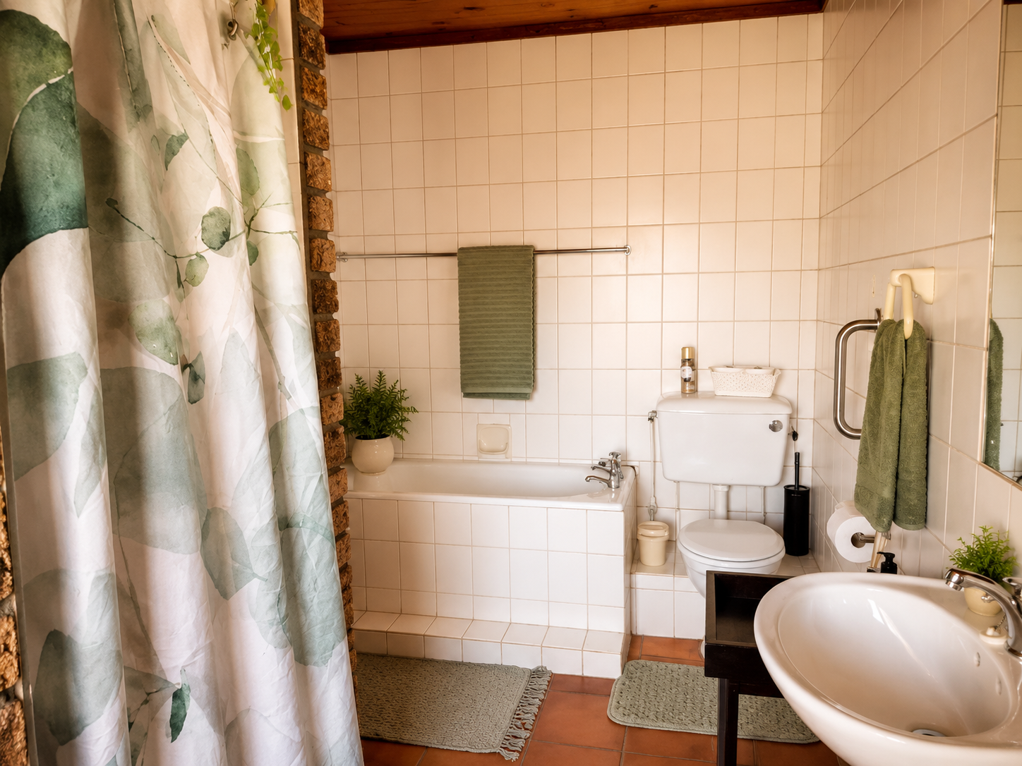 Clean bathroom in the Protea Suite with bath, shower curtain, basin and soft green towels